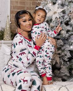 a woman holding a child in front of a christmas tree