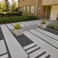 two planters sitting on top of cement blocks in front of a brick building with landscaping