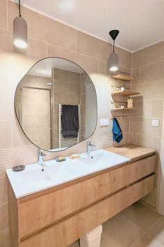 a bathroom with two sinks and a large mirror on the wall above it, along with shelving