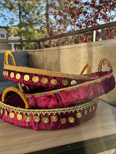 two purple and gold decorated shoes sitting on top of a table