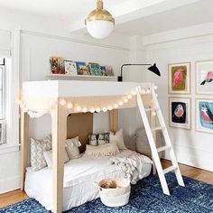 a bedroom with a bunk bed, ladder and pictures on the wall above it that have lights strung from them