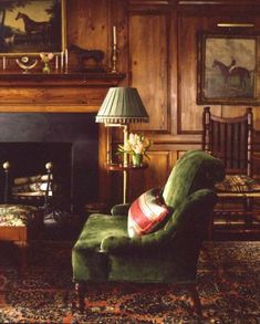 a green chair sitting in front of a fire place next to a painting on the wall