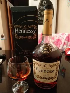 a bottle of hennessy next to a wine glass on a table with a box