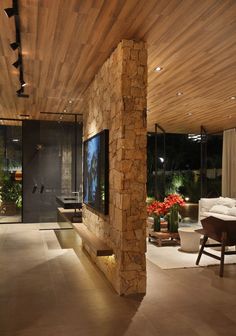 the interior of a modern house with stone columns and wood ceilinging is lit by lights