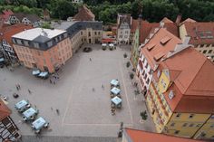 an aerial view of a town square with people walking around and buildings in the background