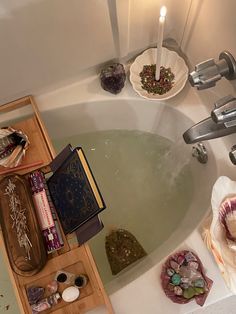 a bath tub filled with lots of different types of items next to candles and books