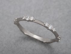 a white gold ring with five diamonds on the top and bottom, sitting on a gray surface