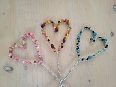 three heart shaped beaded bracelets sitting on top of a wooden table