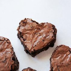 four heart shaped brownies sitting on top of a white table next to each other