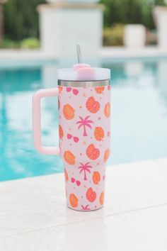 a pink and orange cup sitting on top of a table next to a swimming pool