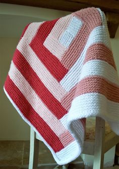 a red and white blanket sitting on top of a wooden table next to a chair