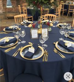 the table is set with blue linens and gold place settings