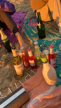 several bottles of alcohol are sitting on the beach towel and towels, along with other items