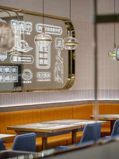 the interior of a restaurant with wooden tables and blue chairs in front of a large mirror