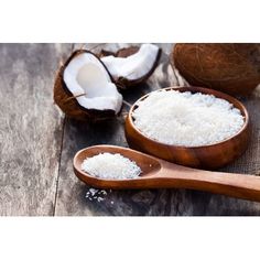 coconuts and sugar in wooden spoons on wood table