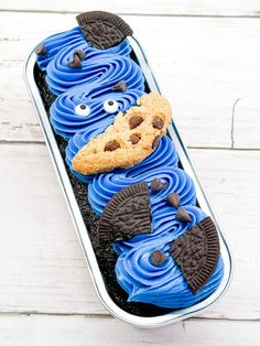 an oreo cookie with blue icing and cookies on top in a metal container