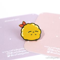 a yellow brooch sitting on top of two pink cards