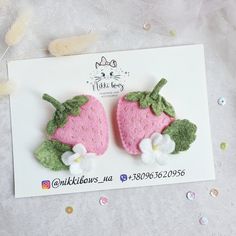 two felt strawberrys with green leaves and white flowers