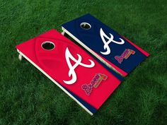 two atlanta braves cornhole game boards laying on the grass with their logos painted on them