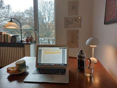 an open laptop computer sitting on top of a wooden table next to a cup of coffee