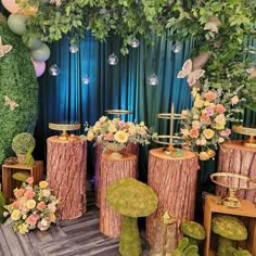 an assortment of wooden stumps with flowers and butterflies on them in front of a backdrop