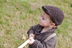 a young child holding a baseball bat on top of a grass covered field in front of a bird