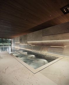 an indoor swimming pool in the middle of a room with wooden walls and flooring