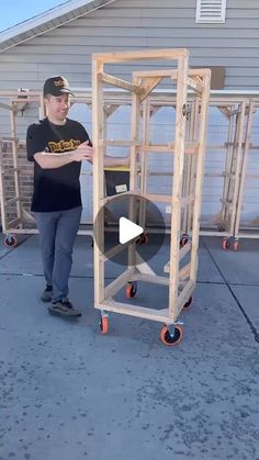 a man standing next to a cart with wheels on it and holding something in his hand