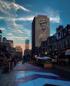 a large mural on the side of a building in an urban area with people walking around