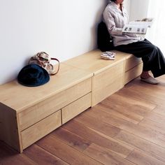 a woman sitting on top of a wooden bench next to a bag and purses