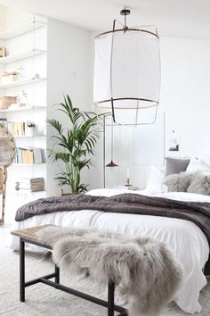 a bedroom with white walls and carpeted flooring is decorated in neutral tones, including fur