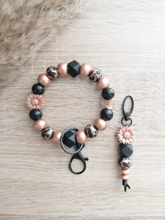 a bracelet with black and pink beads on top of a wooden table next to a pair of scissors