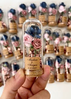 a hand holding a small glass tube with flowers in it