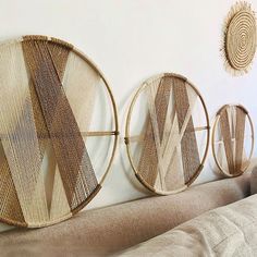 three round woven wall hangings on the wall above a couch in a living room