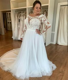 a woman standing in front of a mirror wearing a wedding dress with long sleeves and lace