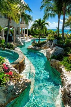 an outdoor swimming pool surrounded by palm trees and water features a waterfall that runs down to the beach