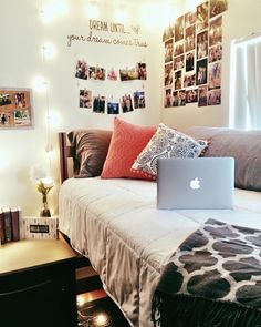 a laptop computer sitting on top of a bed in a room with pictures above it