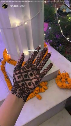 a decorated hand on top of a white box with orange flowers around it and lights in the background