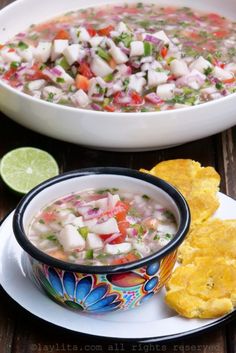 a bowl of mexican soup with tortilla chips next to it on a plate