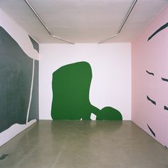 an empty room with black and white artwork on the walls, including a large green silhouette