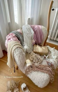 a pile of clothes sitting on top of a wooden floor next to a chair and window