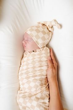 a newborn baby wrapped in a blanket being held by someone's hand while laying down