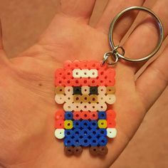 a hand holding a keychain made to look like an old school video game character