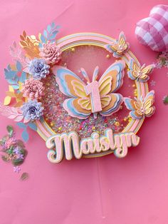 a close up of a paper cut out of a butterfly on a pink background with the word makskyn surrounded by flowers