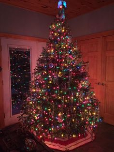 a brightly lit christmas tree in the corner of a room