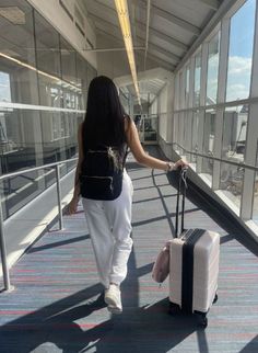 a woman is walking with her luggage down the walkway