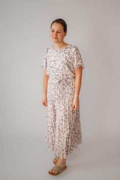 This exquisite floral dress is a statement of elegance and attention to detail with a modest round neckline, delicate pleated skirt, flutter sleeves and a feminine tie waist. In addition, this dress is fully lined - through the sleeves, bodice and skirt, so you can feel securely covered. The Ellison will be a treasure in your wardrobe and lovely for every occasion from bridal showers to church. Style: fully lined, pleated bottom, tie waist, button closure Color: ivory floral Fabric content: 100% Be Intentional, Garment Labels, Pleated Midi Dress, Curated Gifts, Flutter Sleeves, Color Ivory, Bridal Showers, Floral Fabric, Flutter Sleeve