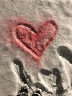 two people are standing in the snow with a heart drawn on it's side