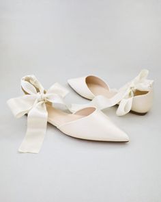 two pairs of white shoes with bows on them