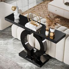 a black and white console table with two vases on it, next to a couch